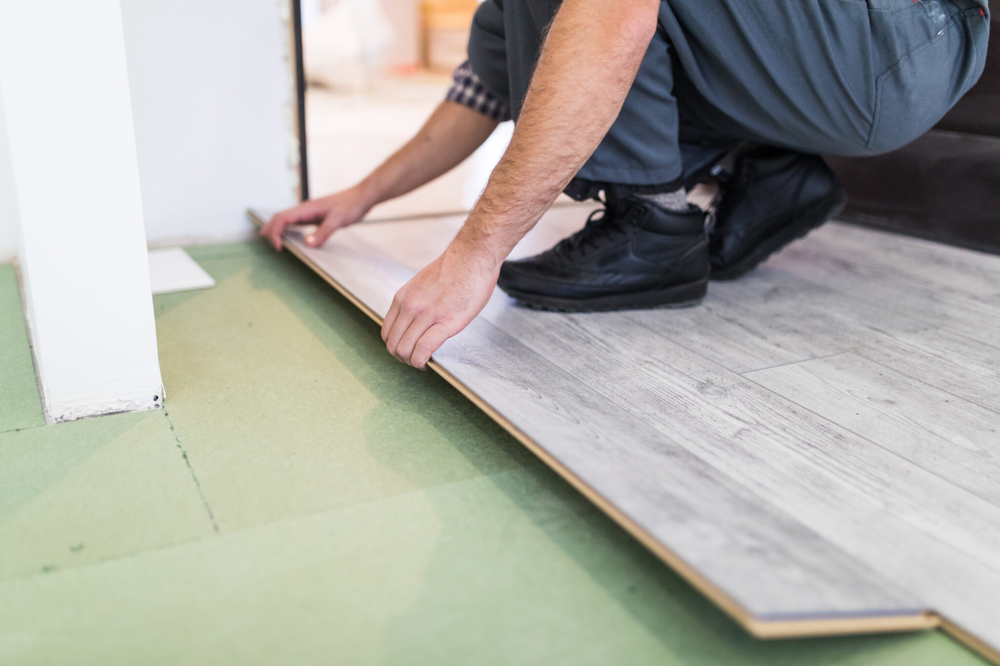 Young worker laying a floor with bright laminated flooring boards